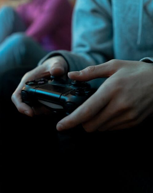 Close-up of hands holding a video game controller, focused in an indoor setting.